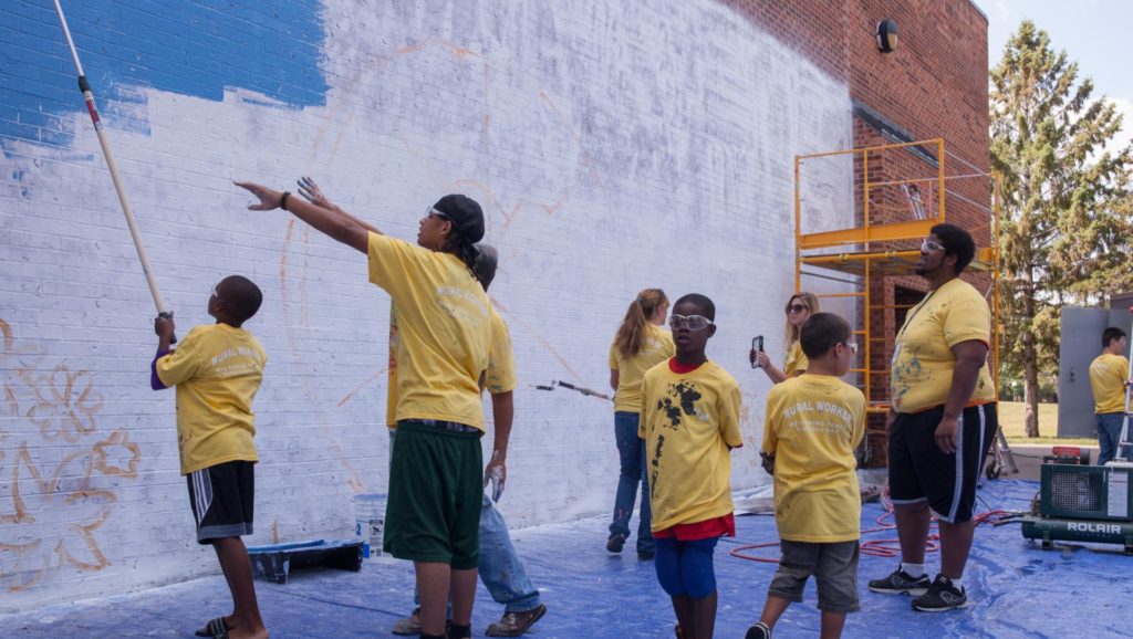 Group of young people in yellow shirts working on mural